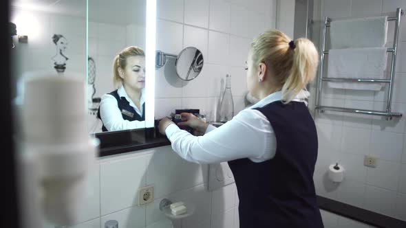 Maid in Uniform Puts Shower Gel for Visitors. Beautiful Interior of Bathroom in Modern Hotel