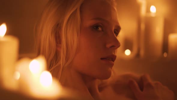 Close Up of a Young Woman Taking a Bath Surrounded By Candles