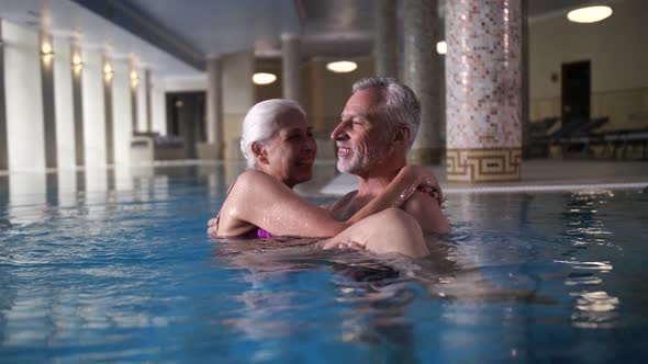 Happy Aging Couple in Swimming Pool of Spa Hotel