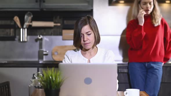 Girl is sitting at table and typing. Home office in the kitchen. online business