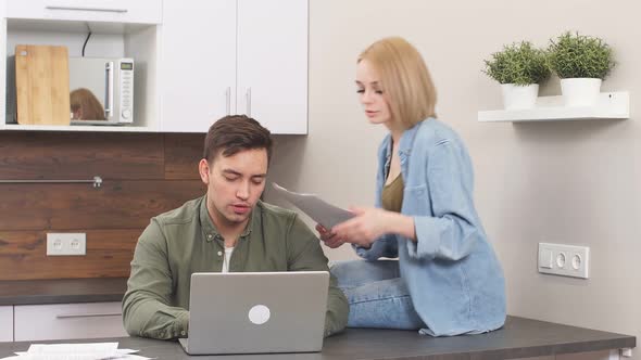 Young Caucasian Spouses Sitting with Modern Laptop and Documents