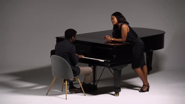 Stylish African American Romantically Sings and Plays a Melody on the Grand Piano for His Beloved
