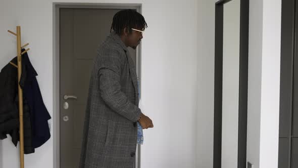 Black Man in Front Home Door Putting on Trendy Coat Leaving House