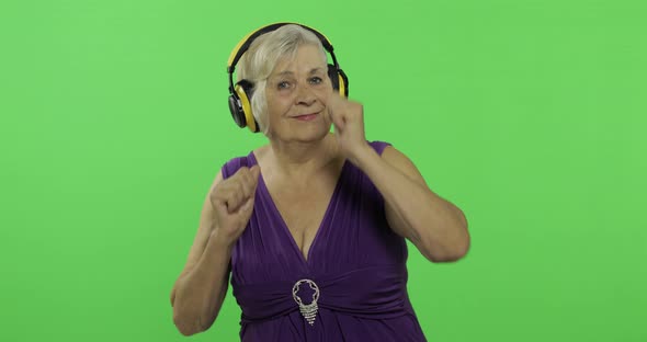 Elderly Woman Listens To Music in Headphones and Dances. Grandmother. Chroma Key