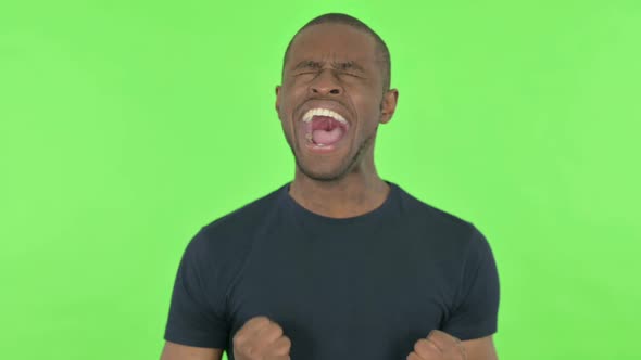 Young African Man Shouting and Screaming on Green Background