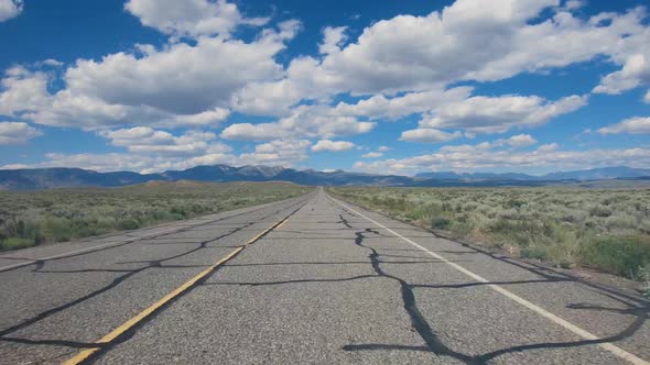 Small Asphalt Road Surrounded By Desert with Clouded Blue Sky.