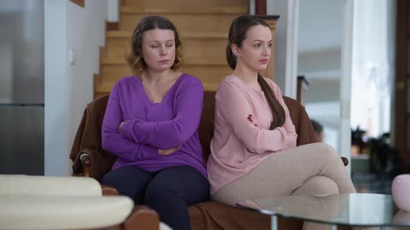 Argued Caucasian Mother and Daughter Sitting Back to Back on Couch at Home in Silence