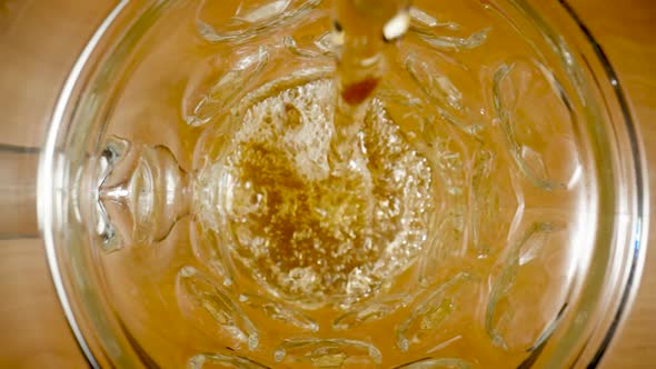 Top View of Stream of Amber Beer Pouring Into Glass