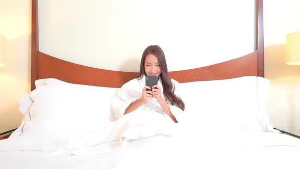 Beautiful Young Woman in Bedroom Checking Social Networks on Bright Morning