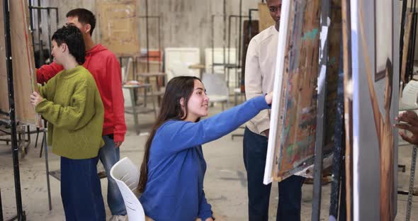 Young multiracial students having fun painting together inside art classroom at college university