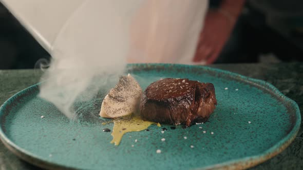 Male Hand Lifts To Up Glass Cloche From a Plate with Hot Food Beef Steak and Moving Smoke