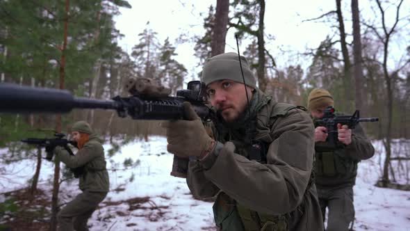 Focused Handsome Man Walking in Slow Motion with Troop in Winter Forest Aiming