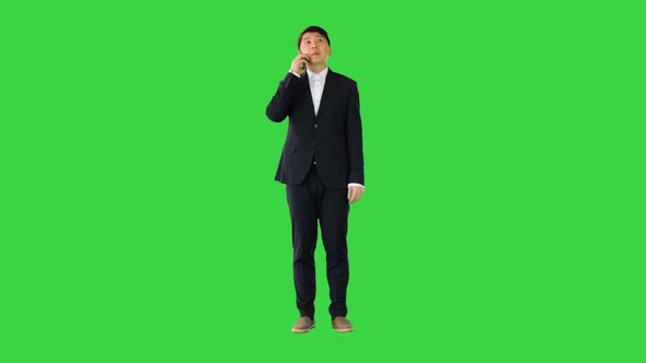 Asian Man in Office Suit Talking on Mobile Phone on a Green Screen Chroma Key