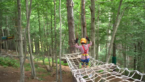 Boy Walks Across a Mesh Bridge  Holding on to a Safety Rope