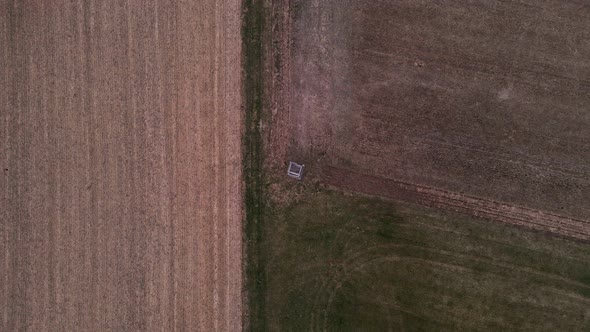 A hunter's deer stand in the middle of green and brown fields in Germany. Aerial high angle view