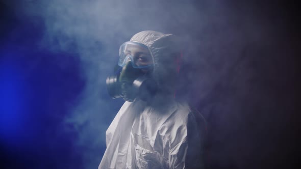 A Woman in White Protective Medicine Suit Disperses the Smoke in the Room