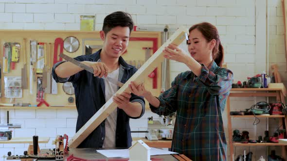 Carpenter workers man and woman measuring wood for built-in furniture project in workshop