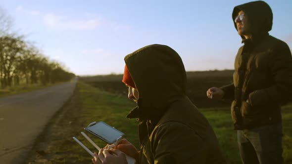 2 Mens Controlling Drone at Sunset Countryside in Red Hat