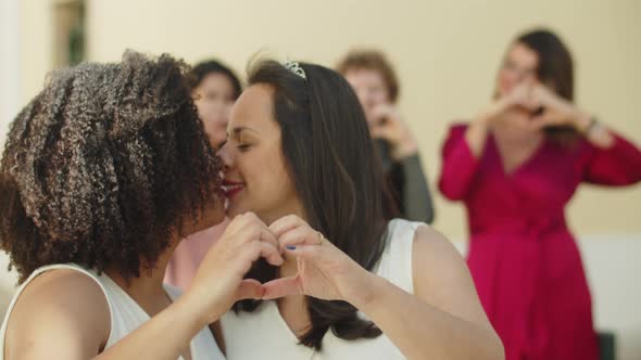 Closeup Shot of Lesbian Newlyweds Showing Heart with Hands