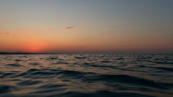 Beautiful low-angle sea-level pov from sailing boat navigating on sea water surface at sunset. Slow-