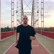Young Man in Black Sports Uniform Runs on the Pedestrian Bridge at Dawn - VideoHive Item for Sale