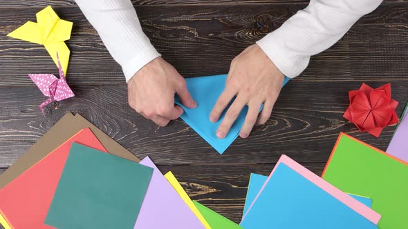Male Hands Folding Blue Paper.