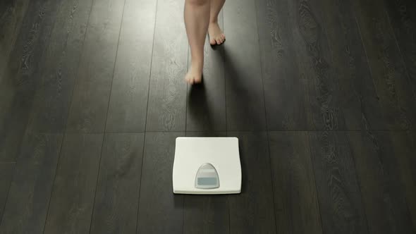 Ineffective dieting, woman with extra body fat weighing herself, dissatisfied