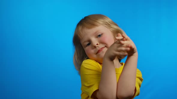 Little Cute Girl Applause and Smiles in the Studio on the Blue Background