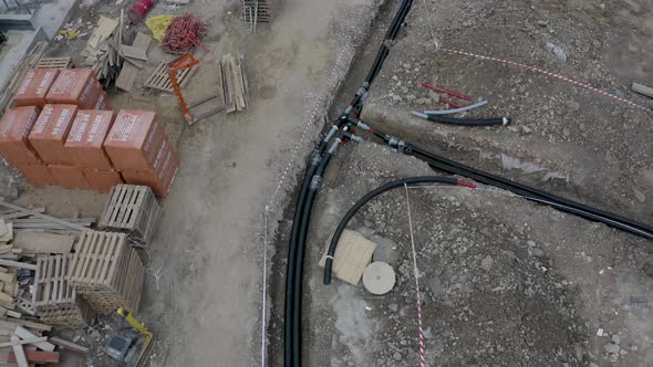 Cables and pipes laid down in an open ditch at a construction site.