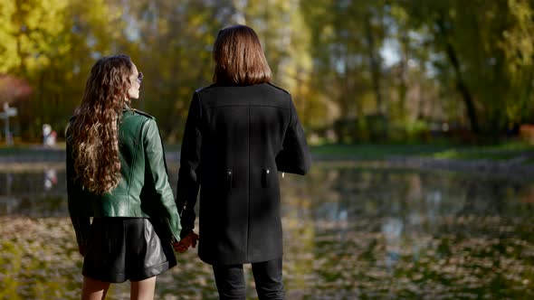 Lovers in Autumn Park Stylish Man and Woman are Holding Hands and Admiring Pond