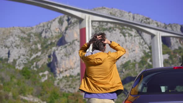 A Man Standing By His Car Looks at the Moracica Bridge in Montenegro