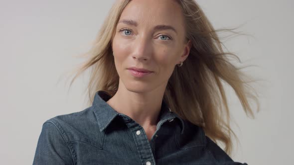 Young Beauty Blonde Woman in Studio Wears Classic Denim with Blowing Hair