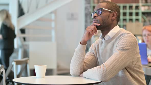 Pensive African Man Thinking in Cafe