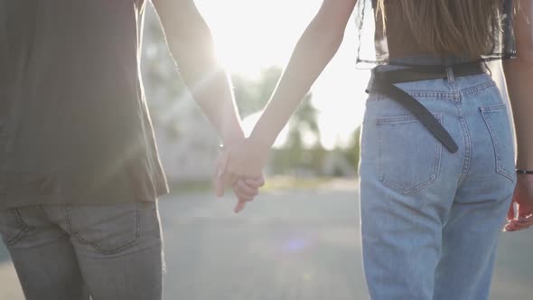 Young Attractive Couple Walking Down the Street Together Hand in Hand on Sunset Backround. Slow