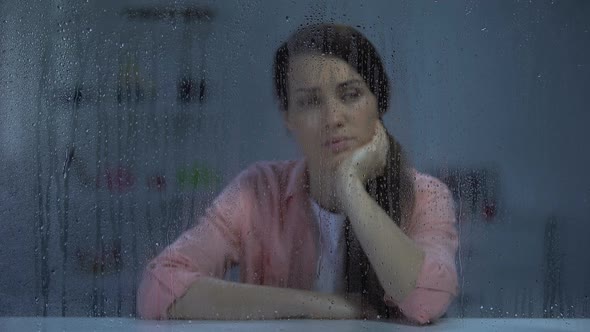 Depressed Young Woman Looking at Camera Through Rainy Window, Life Problems