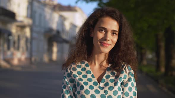 Portrait of Caucasian Cheerful Woman Wearing Dress Smiling While Walking Through Boulevard in