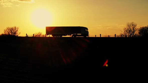 Silhouette of a Moving Truck in a Landscape at Sunset