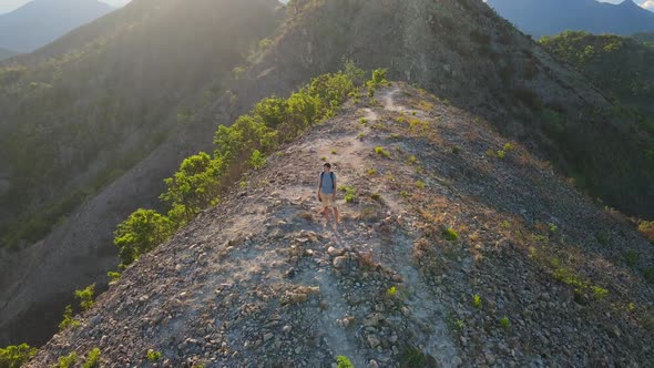 Aerial Shot of a Young Man Standing on Top of the Hill in Mountains. Hiking Concept