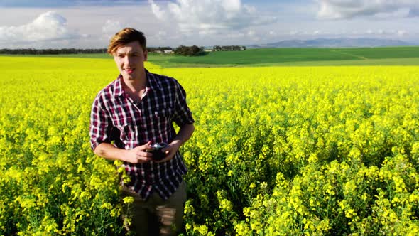 Man taking picture from camera in mustard field