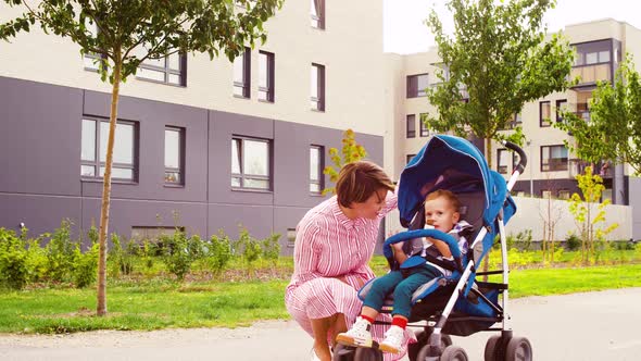 Mother Kissing Son Eating Chocolate in Stroller