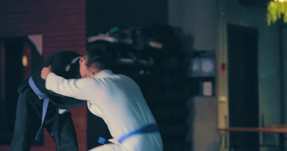 Judo Athletes Train Painful Techniques on the Floor Training Fighters in a Kimono