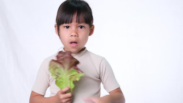 Children do not like to eat vegetables. Little girl who hates eating green salad.