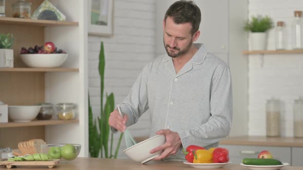 Healthy Young Man Focused While Cooking in Kitchen