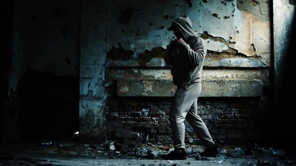 A Young Guy In An Abandoned Building Is Boxing. A Man In A Hoodie Is Boxing