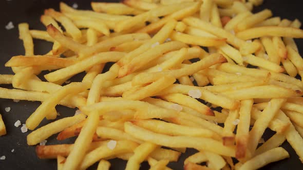 Delicious Golden Fries on a Black Table with Salt Crystals