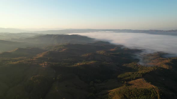 Aerial view of sunrise with fog above mountains. Golden hour and amazing sun rays. Nan, Thailand