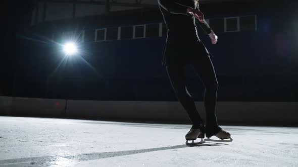 Graceful Figure Skater Woman is Gliding on Ice Rink Closeup View on Her Slender Legs with Skates