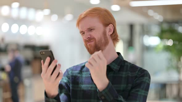 Portrait of Beard Redhead Man Reacting To Failure on Smartphone 