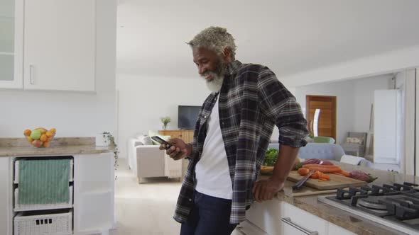 Senior man using smartphone in the kitchen