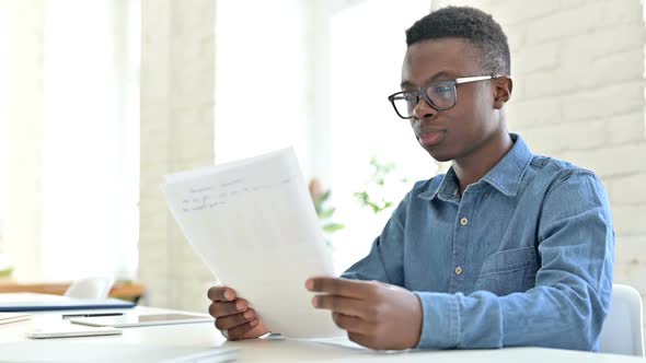 Upset Young African Man Having Loss on Documents in Office